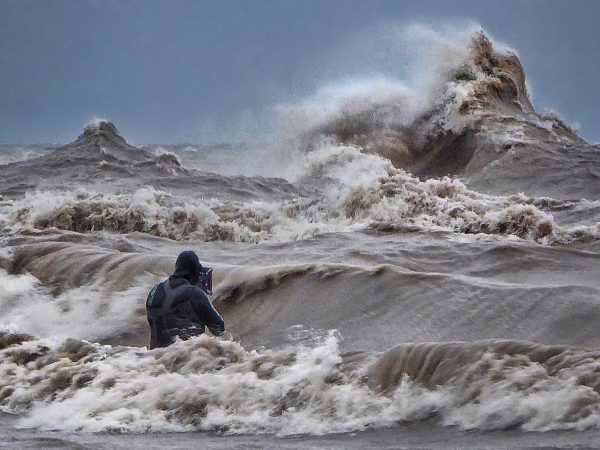 Photographer, Dave Sandford stands in the water to capture waves on Lake Erie. CREDIT DAVID HINTON