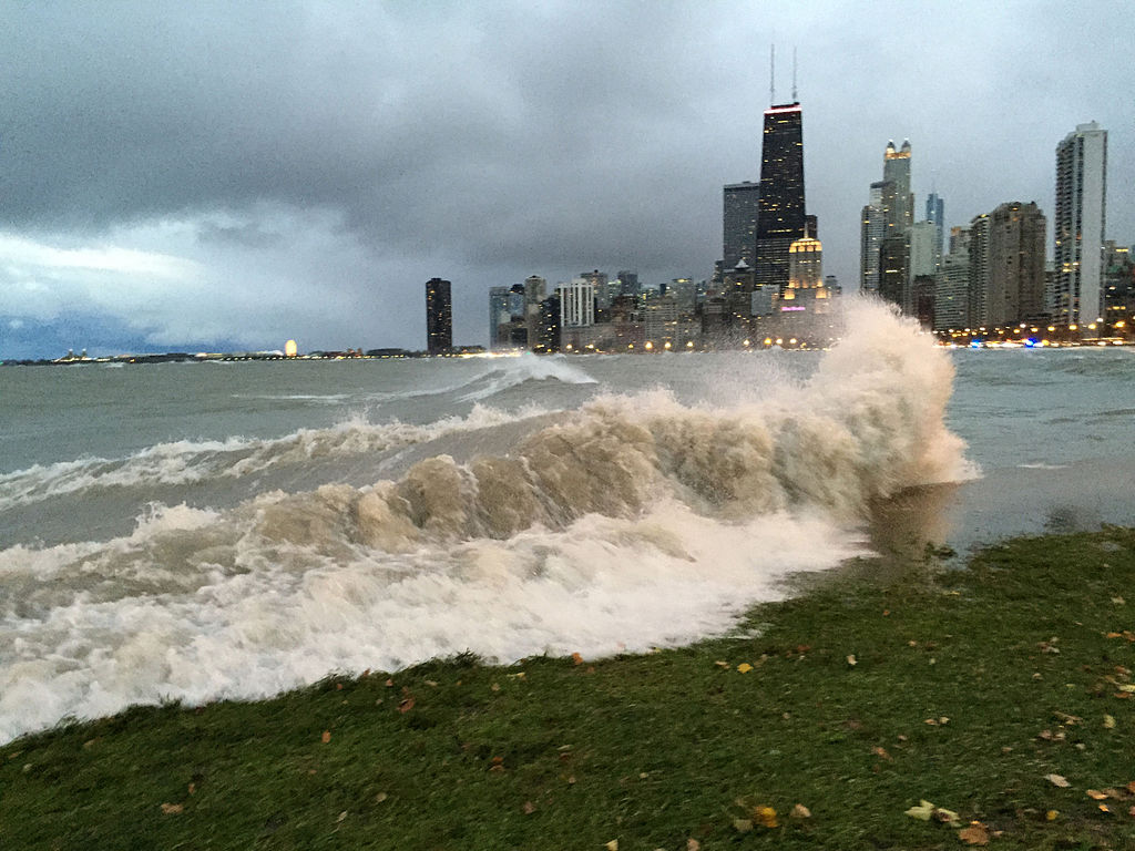 High waves on Lake Michigan shoreline with downtown Chicago skyline in background. Photo via Wikimedia Commons by NOAA Great Lakes Environmental Research Laboratory